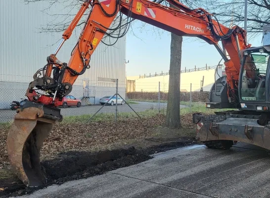 Een kraan van de stad graaft de berm af